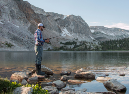 Male angler fishes at a lake in the Snowy Range