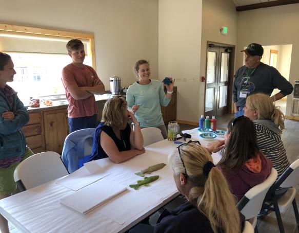 a group of adults watches as someone presents